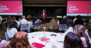 People seated at tables facing a person at a podium with "Louie Awards 2026" banners in the background.