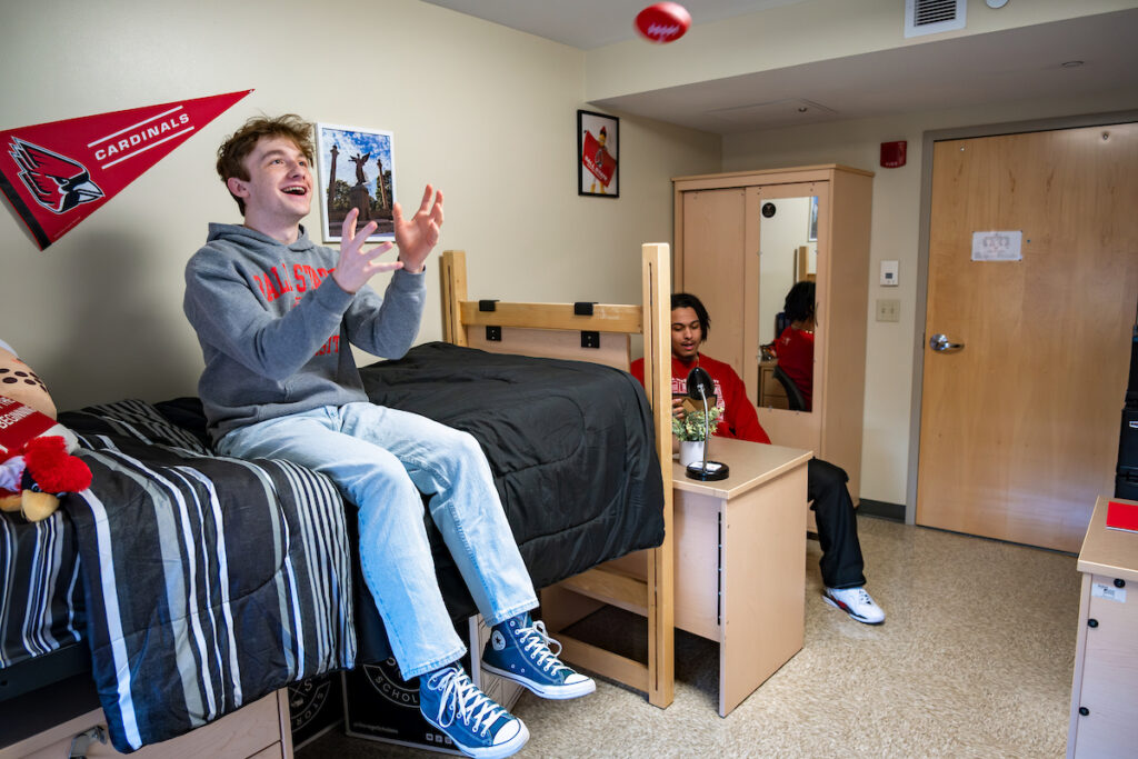 Students tossing a small football in a dorm room.