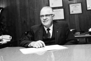 Ralph J. Whitinger sits at a desk in his office.