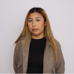 Headshot of a young lady wearing a black shirt and a tan jacket over it.