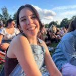 Young girl in overalls sitting in a crowd at a concert.