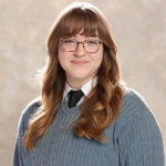 Young lady headshot photo wearing a gray sweater.