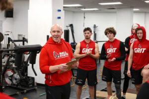 Bill Zenisek stands in the Worthen Arena weight room surrounded by Ball State University baseball players at the conclusion of the team’s weight-lifting session. Bill is the program coordinator for the Master’s in Athletic Coaching degree and the Director of Baseball Performance.