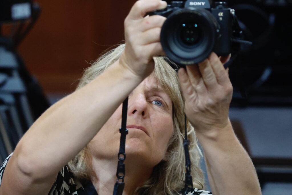 Photographer Susan Walsh holds camera above her head to take a photo.