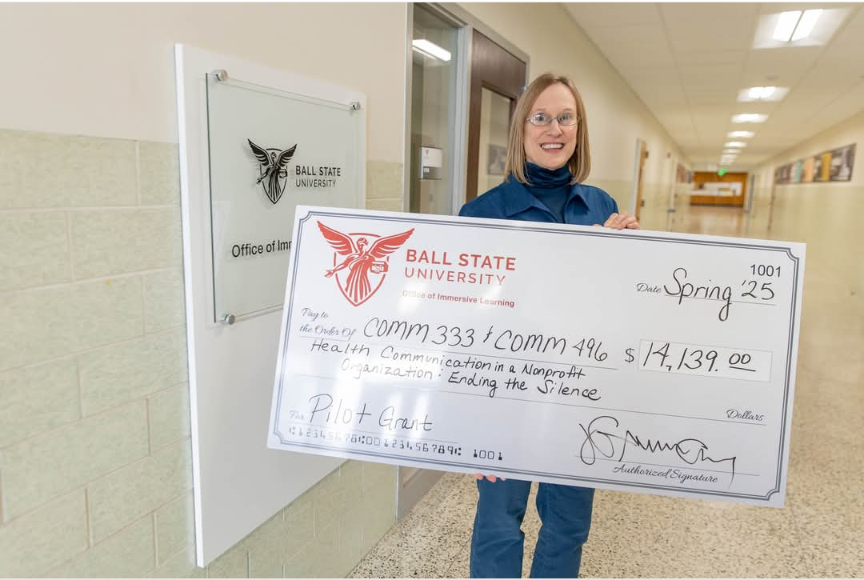 Marcy Meyer holding a giant check for the Spring 2025 Provost Immersive Learning Pilot Grant.