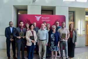 Dean McCauliff and all of the CCIM Faculty award winners pose in front of the CCIM banner to acknowledge their accomplishments.