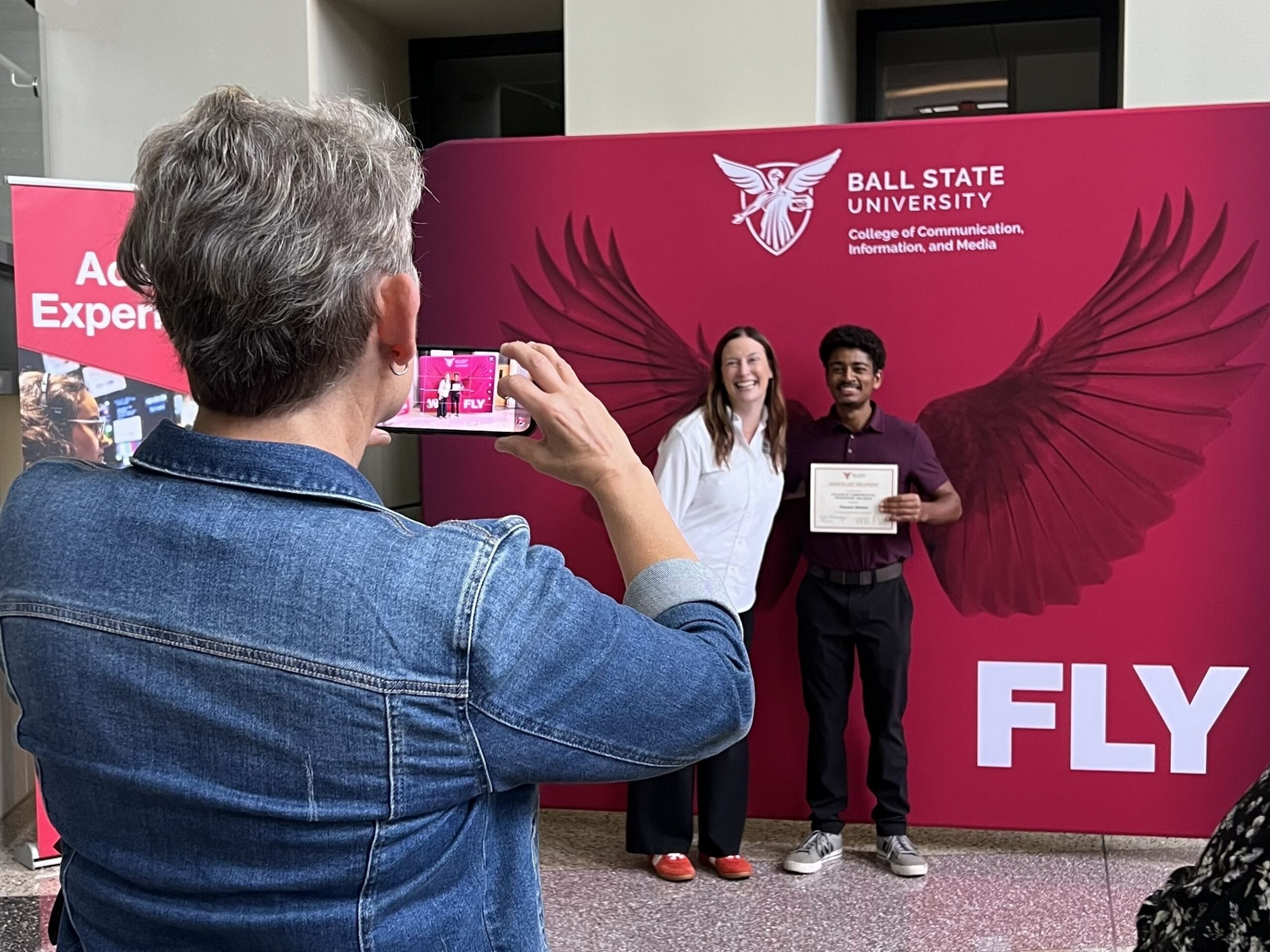 Professor in Communication Studies Laura O'Hara takes a photo of Dean Kristen McCauliff posing with a student. 