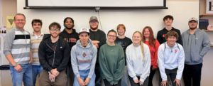 Dr. Adam Kuban stands with his Journalism 322 class for a photo in a classroom.