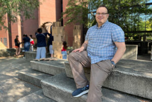 Brenden's outside sitting on concrete steps with kids from DesignWork are working on assembling their projects in the background