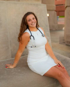 Taylor Burket taking a graduation photo with a stethoscope around her neck.