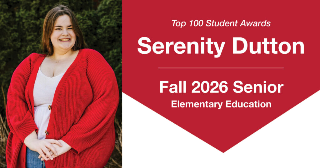 Header graphic for a Top 100 Student Awards blog post. On the left is a photo of Serenity Dutton, a young woman with long brown hair, standing outdoors with her hands folded in front of her and smiling at the camera. She is wearing a white shirt, jeans, and a bright red cardigan. Green evergreen foliage is visible in the background. On the right side of the graphic, text reads: “Top 100 Student Awards,” “Serenity Dutton,” “Fall 2026 Senior,” and “Elementary Education.”