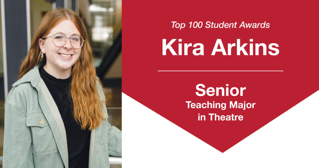 Header graphic for a Top 100 Student Awards blog post. On the left is a photo of Kira Arkins, a young woman with long red hair, standing indoors beside a metal railing with one hand resting on it. She is smiling at the camera and wearing a black T-shirt layered under a light green collared button-up shirt. The background is softly blurred. On the right side of the graphic, text reads: “Top 100 Student Awards,” “Kira Arkins,” “Senior,” and “Teaching Major in Theatre.”