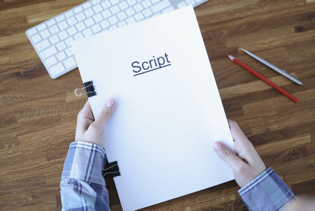 Overhead shot of an individual holding a neatly bound stack of papers labeled "Script" in a clean, modern font.