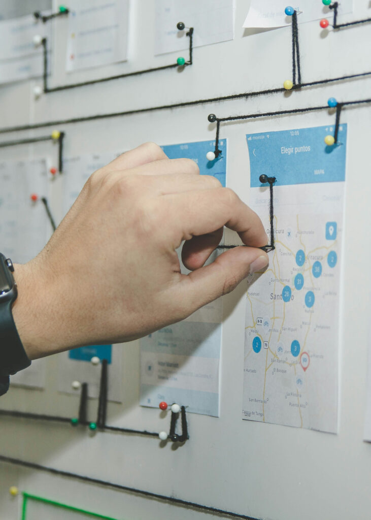 Image of documents pinned to a wall with strings of yarn stretching between them, charting a path from one image to the next.