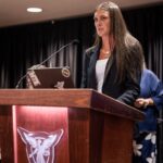 Student Gracee Gibson speaks at podium to give award to Rebecca Brey, the professor she nominated for the Accessible Teacher Award