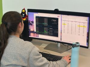 A student with long flowing dark ponytail hairstyle, gazes at a large computer monitor and appears to be using data analysis software in the STAR lab.
