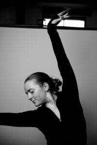 Annika in a dance pose, with one arm in the air