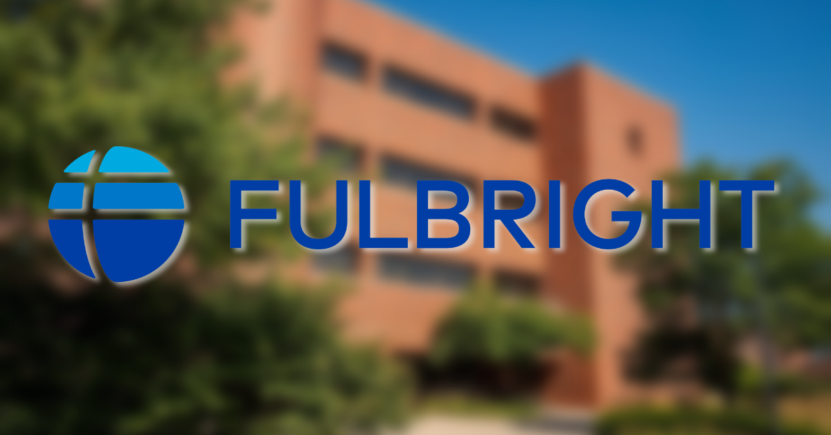 Blue logo in front of a blurred brick building